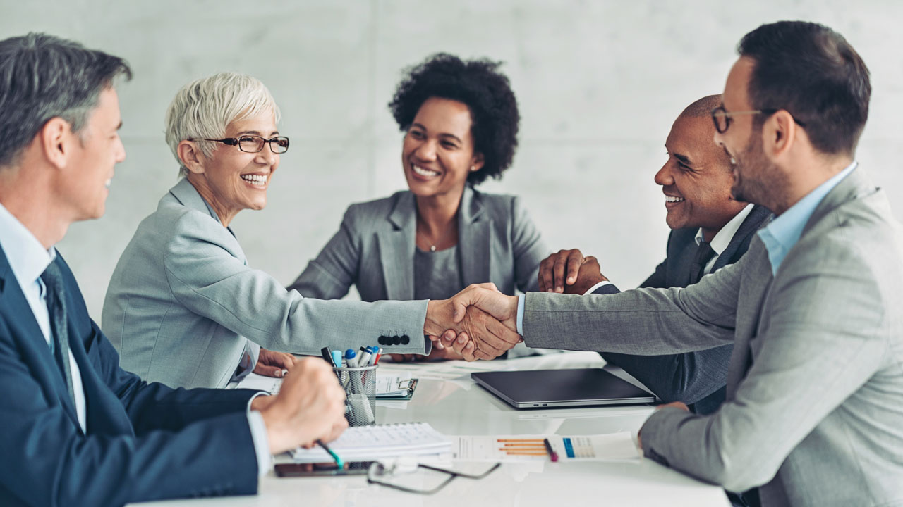 A group of people having a meeting and two of them are shaking hand